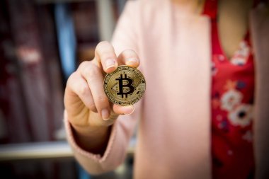bir kadının elinde altın bitcoin