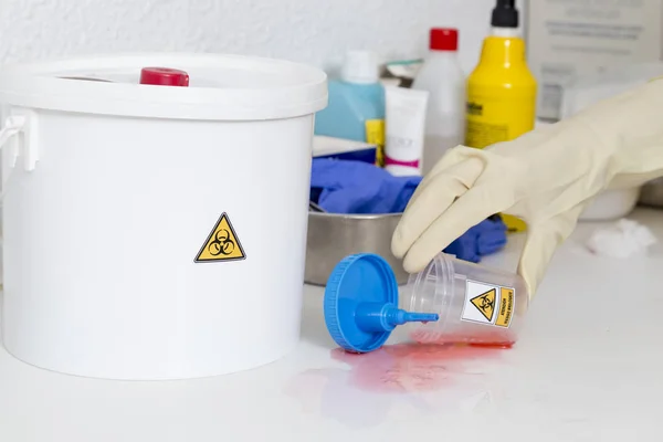 stock image person cleaning a waste container labeled as biological risk