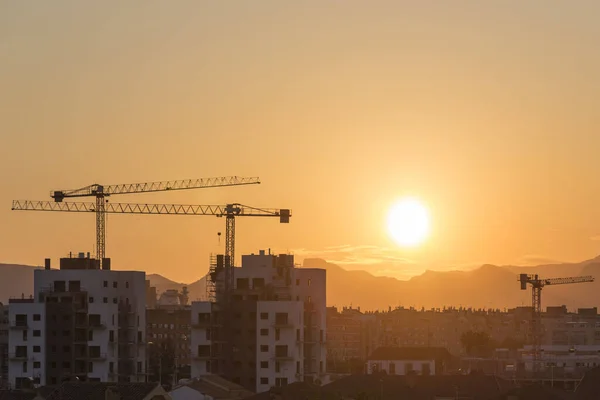 Sagunto 'da gün batımı, vinçli ve güneşli iki bina, Valencia, İspanya