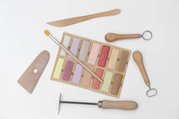 set of modeling tools for ceramics, cutters, toothpick, trowel and a sample of enamels, on white background