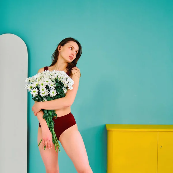 A young fitness girl in sportswear with flowers in her hands posing for a picture — Stock Photo, Image