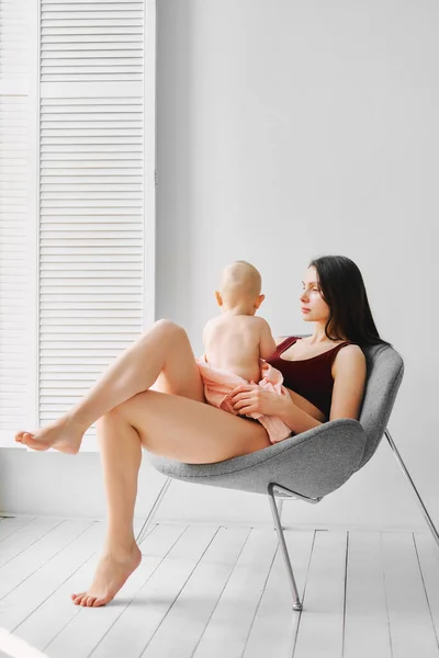 Jovem mãe com um bebê sentado em uma cadeira — Fotografia de Stock