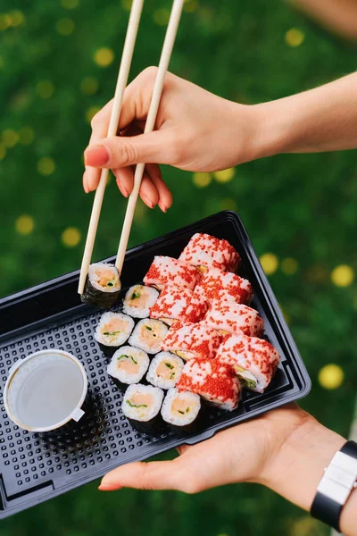 Hand holding sushi roll using chopsticks — Stock Photo, Image