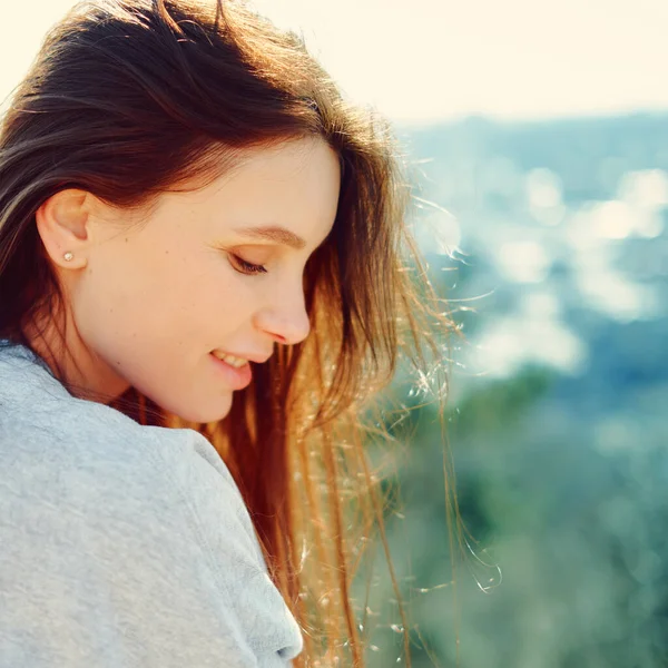 Seitenansicht eines lächelnden Mädchens vor einem Hintergrund der Natur. Nahaufnahme — Stockfoto