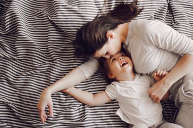 Üç yaşında bir kızı olan güzel bir anne çizgili yatakta yatarken sarılıp güler.