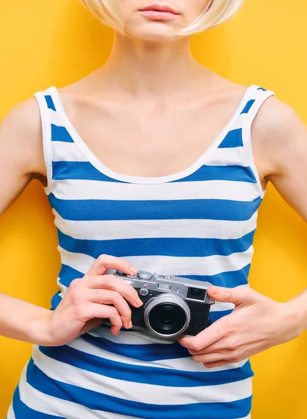 Portret dziewczyny z kamerą w dłoni na żółtym tle. Odizolowane studio — Zdjęcie stockowe