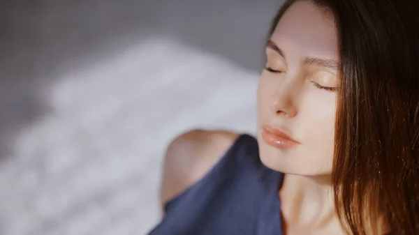 Portrait of a girl with closed eyes sitting on a carpet in the morning sun — Stock Photo, Image