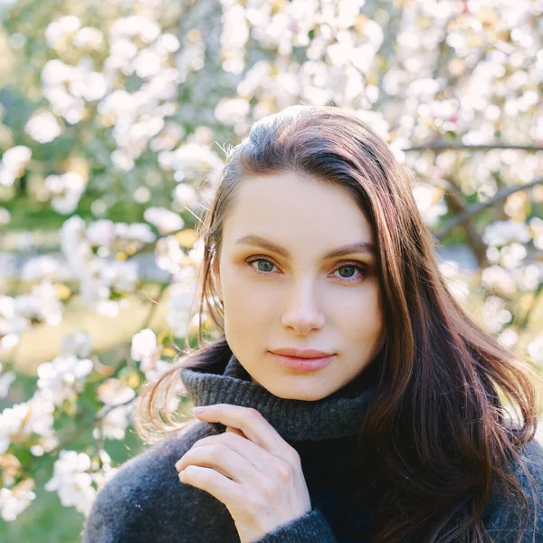 Porträt der schönen jungen Frau in Apfelbäumen blühenden Park an einem sonnigen Tag. Dunkle Haare. Glückskonzept. — Stockfoto