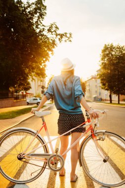 Şapkalı güzel bir kızın portresi. Arka planda bisiklet var. Gün ışığında.
