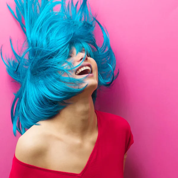 Retrato de estudio de una hermosa chica sexy con una sonrisa en movimiento sobre un fondo rosa. Chica con el pelo azul — Foto de Stock