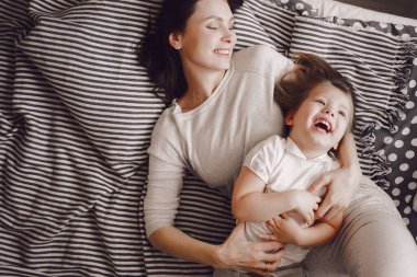 Üç yaşında bir kızı olan güzel bir anne çizgili yatakta yatarken sarılıp güler.