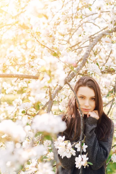 Porträt junge Frau in Apfelbäumen blühenden Park an einem sonnigen Tag. Dunkle Haare. Glückskonzept. — Stockfoto