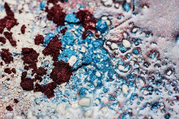 Blue, white and dark red Powder Pieces on Oil