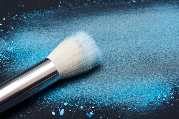 Cepillo de maquillaje blanco sobre polvo azul manchado — Foto de Stock