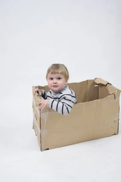 Uma criança pequena senta-se na caixa — Fotografia de Stock