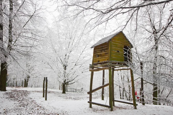 El bosque cubierto de nieve y la cabaña infantil sobre el árbol . — Foto de Stock