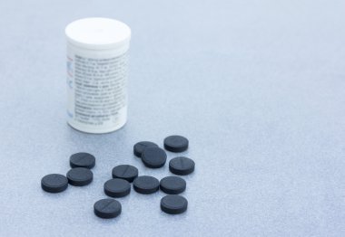 Gri arka planı portre üzerinde vücut temizliği için aktif kömür tabletleri. Senin metin için ile yer