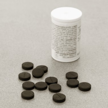 Activated Charcoal Tablets For Cleansing The Body On A Gray Background Closeup. Black And White Photo clipart