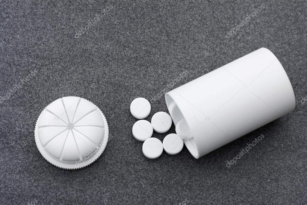 White Pills Scattered On A Gray Background And An Open Bottle. Top View Closeup