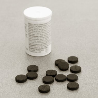 Activated Charcoal Tablets For Cleansing The Body On A Gray Background Closeup. Black And White Photo clipart