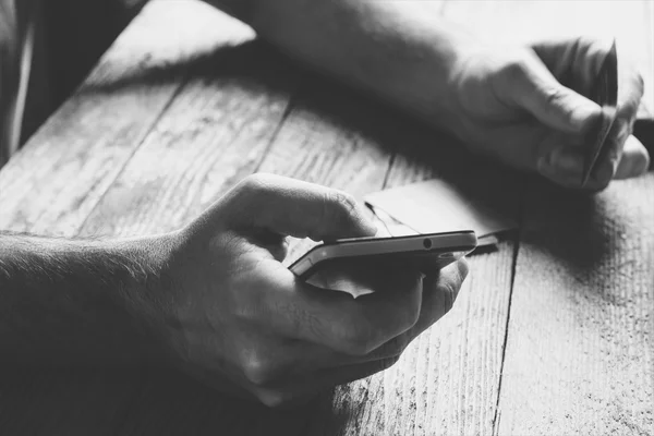 Man Hands segurando cartão de crédito e usando telefone celular à noite. Compras online, serviços bancários online e marketing online. profundidade rasa do campo, foto tonificação preto e branco — Fotografia de Stock