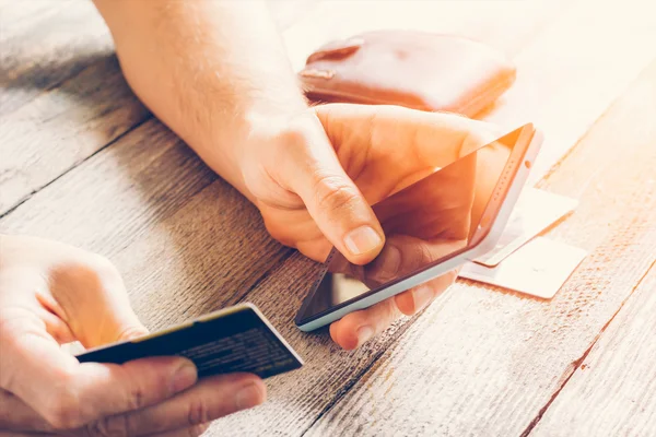 Man Hands memegang kartu kredit dan menggunakan ponsel di bawah sinar matahari. Belanja online, online banking dan pemasaran online. kedalaman field yang dangkal, foto toning — Stok Foto