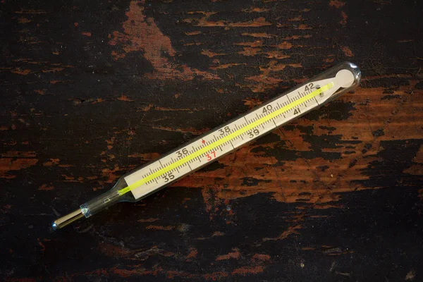 Altes medizinisches Quecksilber-Thermometer auf schwarzem Grunge-Holzhintergrund, Draufsicht — Stockfoto