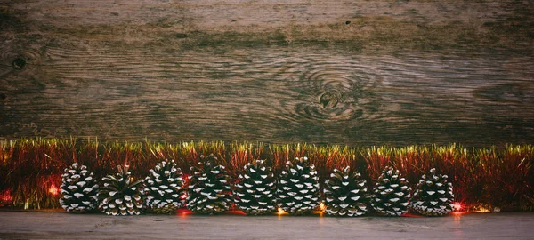 Fundo de madeira velho com cones de abeto, ouropel vermelho e guirlanda com espaço para texto. o conceito de Natal de Ano Novo. foto matizado — Fotografia de Stock