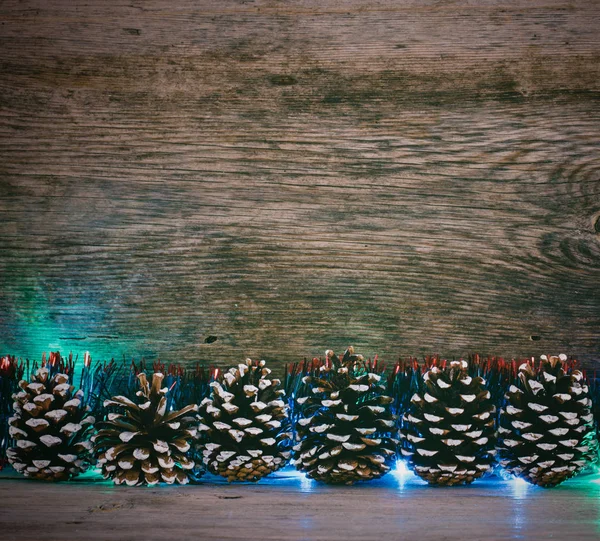 Antecedentes de Ano Novo. cones de abeto, ouropel azul e luzes guirlanda em um celeiro velho placas. Foto matizada — Fotografia de Stock