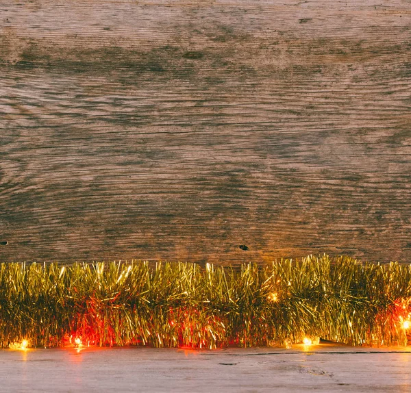 Świąteczny Bożego Narodzenia tło. Złote blichtr i świateł girlanda na stare deski stodoły. Przyciemnione zdjęcie — Zdjęcie stockowe