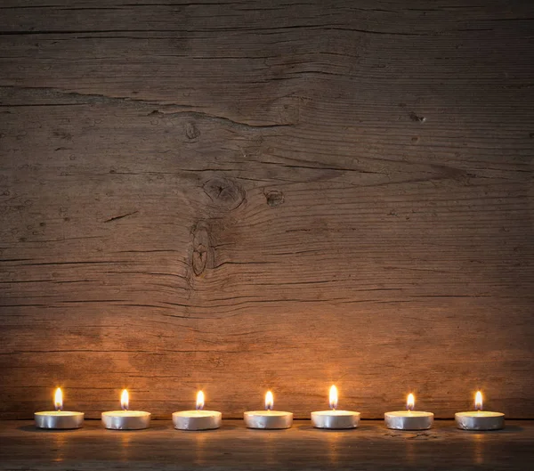 Burning candles on the background of old barn boards — Stock Photo, Image