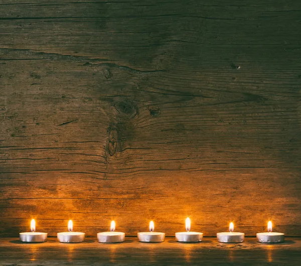 Burning candles on the background of an old barn board, toned photo — Stock Photo, Image