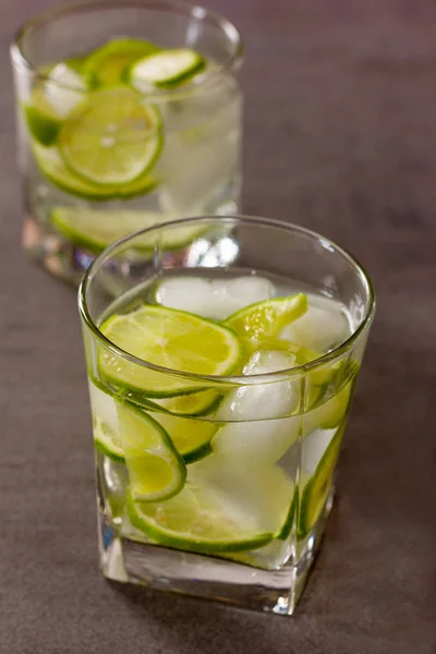 Cocktail refrescante com limão verde e gelo de perto — Fotografia de Stock