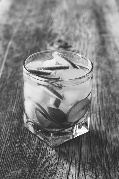Cocktail Margarita with lemon and ice cubes in an old wooden table closeup, black and white photo — Stock Photo, Image