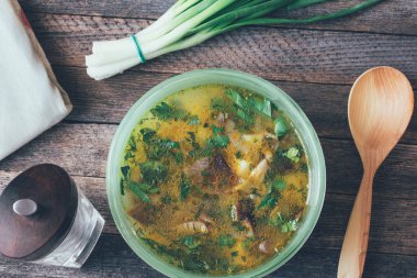 bir kase, yeşil soğan, karabiber değirmeni ve eski ahşap masa üzerinde bir tahta kaşık mantar çorbası. portre, yukarıdan görünüm. renkli fotoğraf