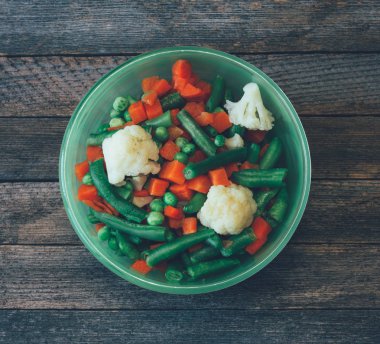 Asya Mutfağı çanağı. havuç, bezelye, fasulye, karnabahar eski ahşap masa, yakın çekim üstten görünüm üzerinde yeşil bir kase sebze karışımı. renkli fotoğraf