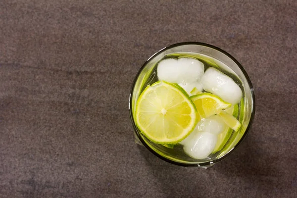 Cocktail alcoólico com limão verde e closeup de gelo vista superior — Fotografia de Stock