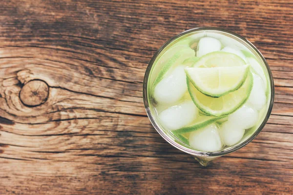 Refreshing lemonade with green lemon and ice close-up view from above, toning photo — Stock Photo, Image