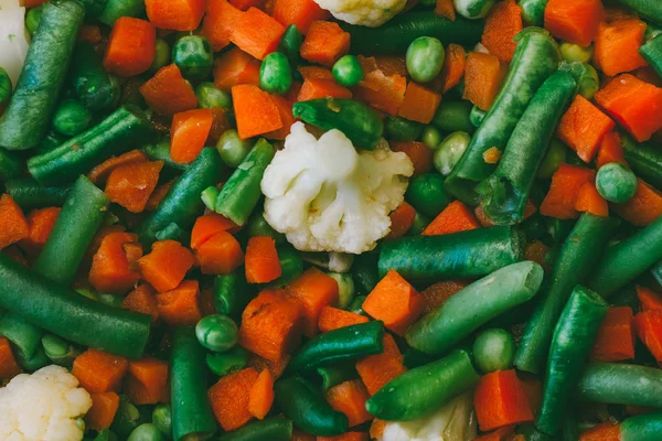 Groente mix van wortelen, erwten, groene bonen en bloemkool dicht omhoog, bovenaanzicht, getinte foto — Stockfoto