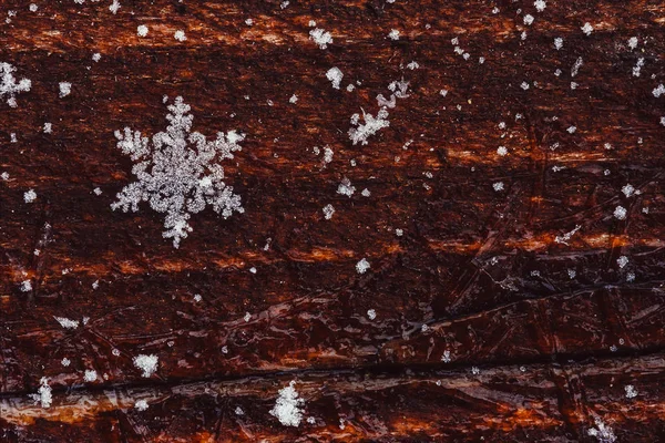 Fiocco di neve naturale su uno sfondo marrone in legno con spazio per il testo. pho colorato — Foto Stock