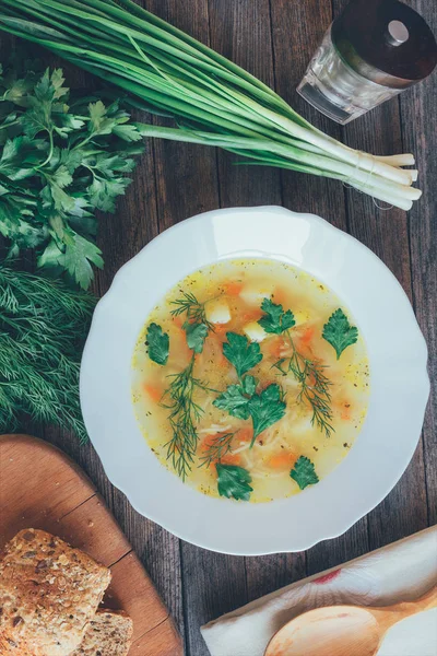 Soup with noodles and greens, corn bread and bundles of onions, parsley and dill. top view close-up. tinted photo — Stock Photo, Image