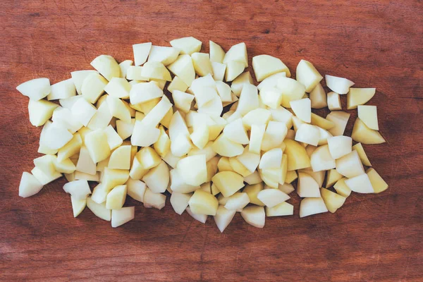 Skivad rå potatis på en gammal cutting Board. ovanifrån nära upp, tonade foto — Stockfoto