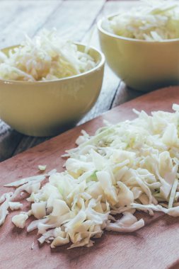 Eski kesme tahtası üzerinde çiğ lahana dilimlenmiş ve seramik kaseler, renkli fotoğraf kapatmak