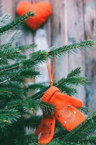 Rode baby wanten opknoping op de takken van een Spar en een rood pluche hart op de achtergrond, getinte foto — Stockfoto