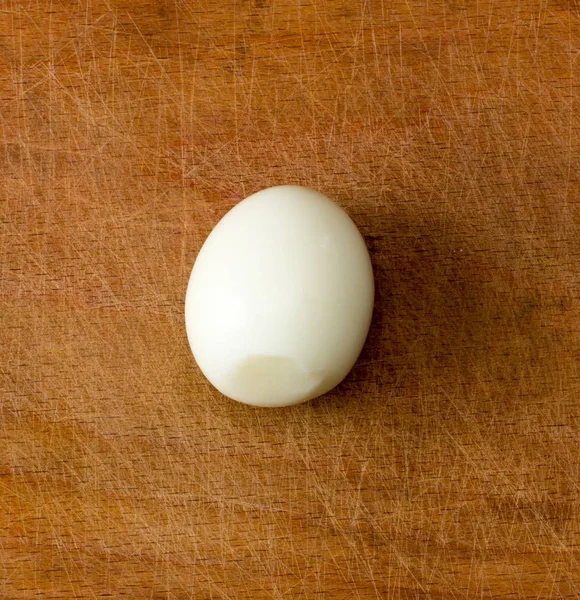 Peeled boiled egg on an old cutting board. view from above close-up — Stock Photo, Image