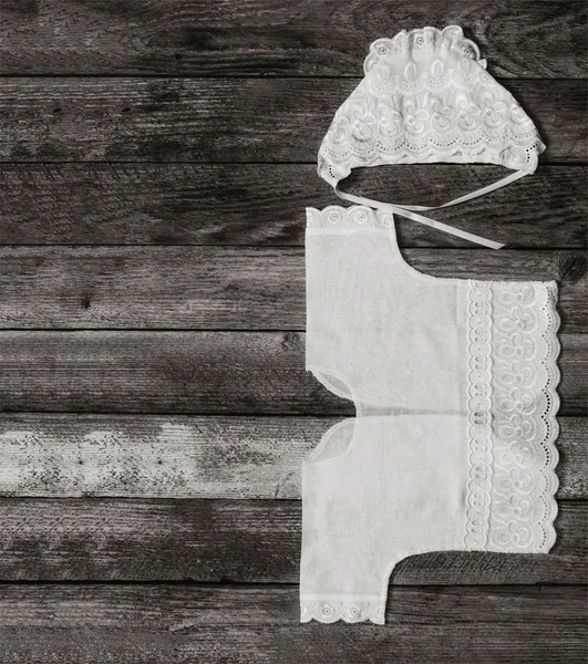 Black and white photo of a cap and shirt for a newborn on an old rustic wooden table closeup, top view. with space for your text — Stock Photo, Image