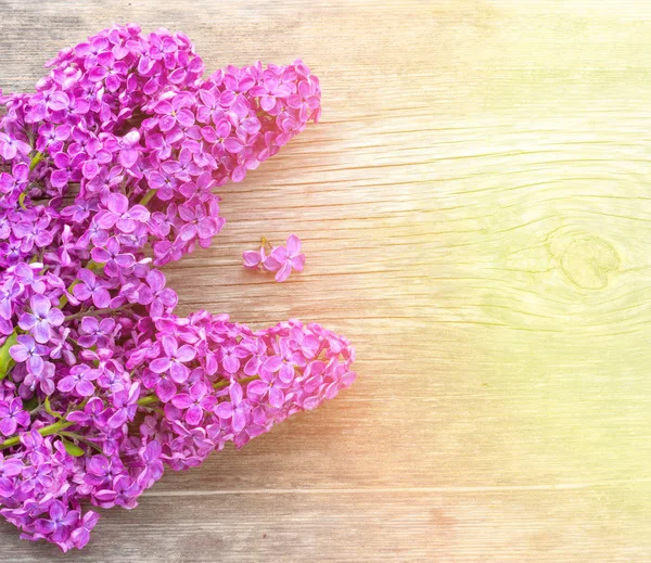 Fundo de primavera brilhante com um buquê de flores lilás em uma placa de madeira na luz solar dourada, com espaço para texto — Fotografia de Stock