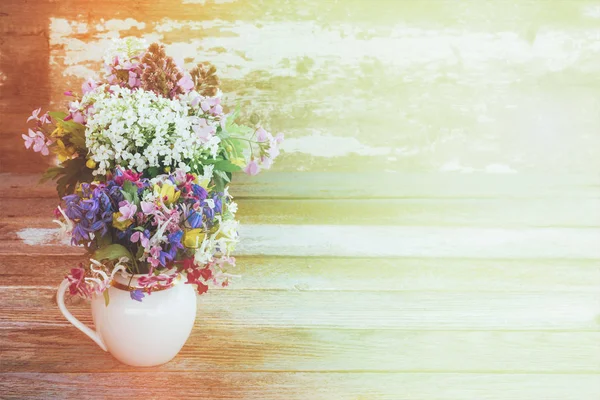 Fond de printemps avec des fleurs sauvages dans une cruche blanche à la lumière douce du soleil — Photo