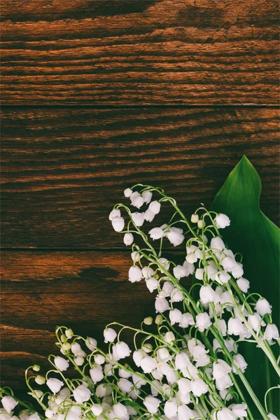 Fleurs forestières lis de la vallée sur un fond de planches de bois brun. Teinte photo avec espace pour le texte — Photo