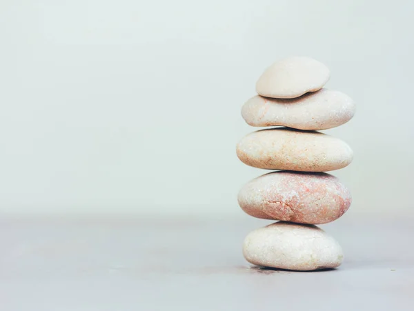 Uma pilha de pedras rosa lisas em um fundo cinza com espaço para texto — Fotografia de Stock